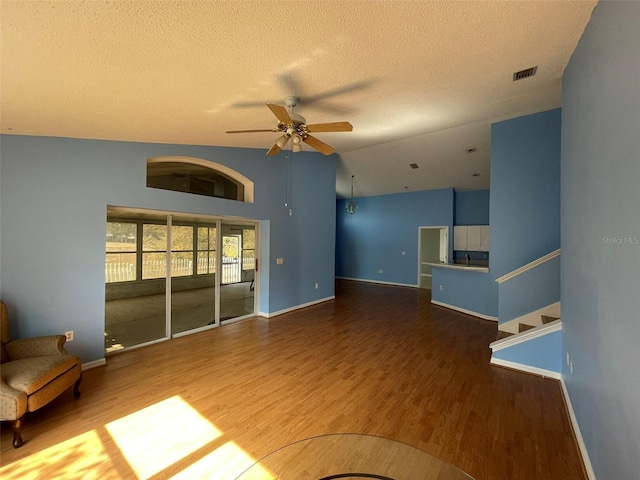 unfurnished living room with hardwood / wood-style flooring, ceiling fan, vaulted ceiling, and a textured ceiling