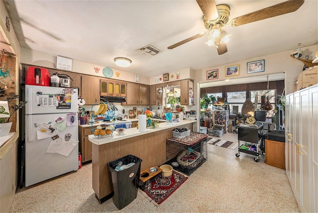 kitchen with white refrigerator, ceiling fan, and kitchen peninsula