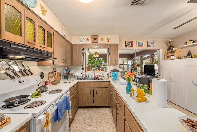 kitchen with white electric stove, sink, and a textured ceiling