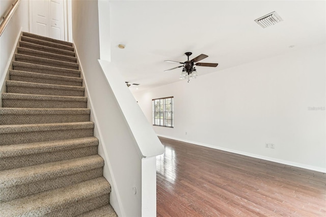 staircase with hardwood / wood-style flooring and ceiling fan