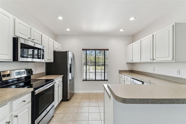 kitchen with light tile patterned floors, stainless steel appliances, kitchen peninsula, and white cabinets