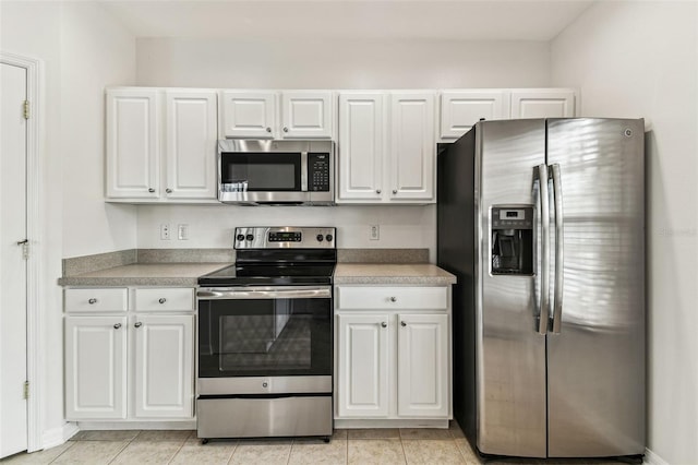 kitchen with light tile patterned flooring, appliances with stainless steel finishes, and white cabinets