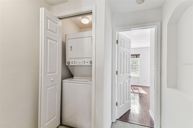 laundry room with wood-type flooring and stacked washer and clothes dryer