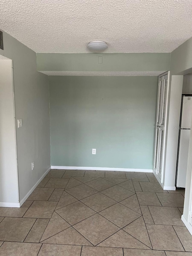 empty room with light tile patterned floors and a textured ceiling