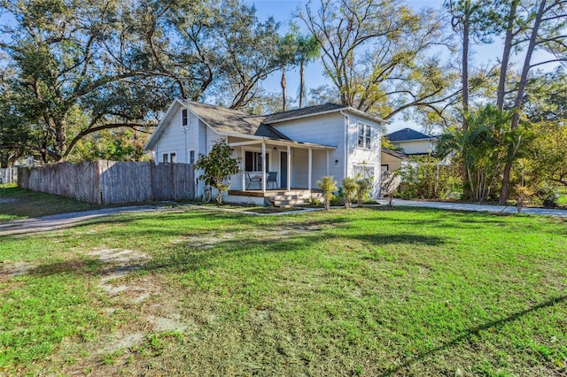 view of front of house featuring a porch, fence, and a front lawn