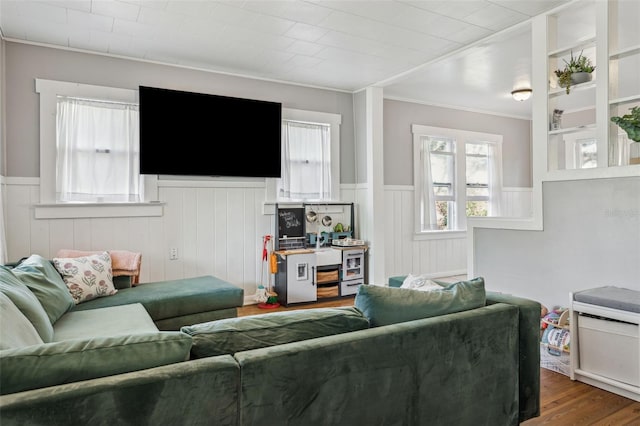 living room with wood finished floors, a wainscoted wall, and ornamental molding