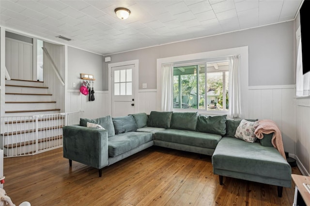 living room featuring stairs, a healthy amount of sunlight, a wainscoted wall, and wood-type flooring