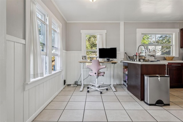 office space with light tile patterned floors, a wainscoted wall, crown molding, and a sink