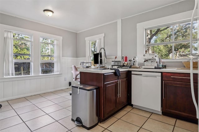 kitchen featuring crown molding, light tile patterned floors, dishwashing machine, wainscoting, and a peninsula