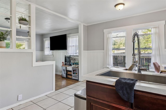 kitchen with light tile patterned floors, a wainscoted wall, and a wealth of natural light