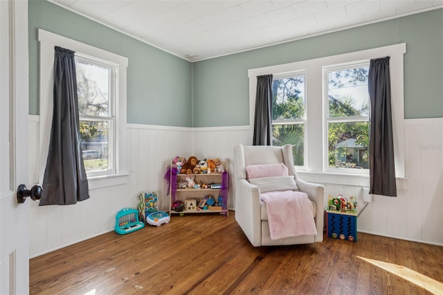 living area with wood-type flooring and wainscoting