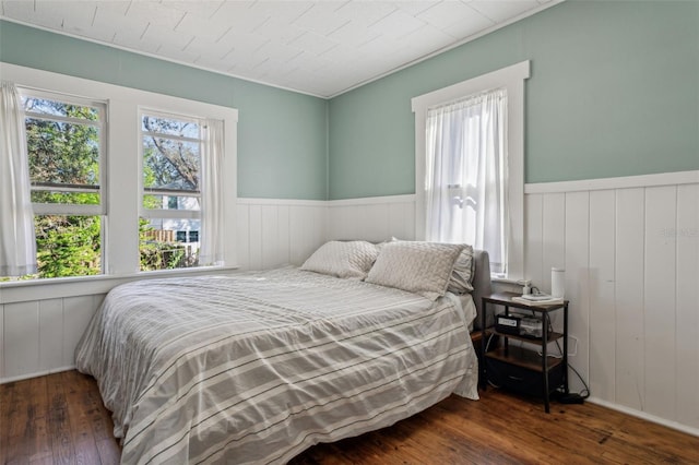 bedroom with wood-type flooring and wainscoting