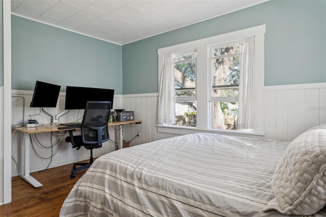 bedroom with wood finished floors and wainscoting