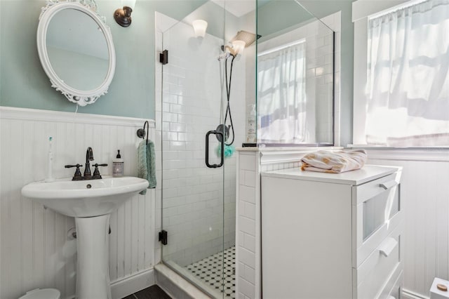 full bath featuring a sink, a shower stall, and wainscoting