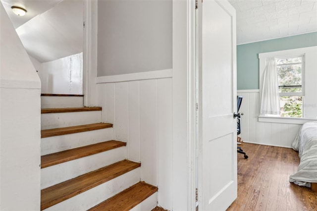 staircase with a wainscoted wall and hardwood / wood-style floors