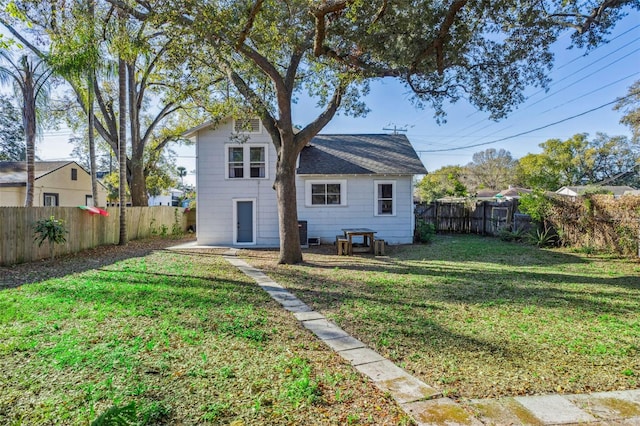 back of house featuring a yard and a fenced backyard