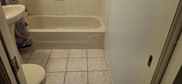 bathroom featuring a tub to relax in, tile patterned floors, and toilet