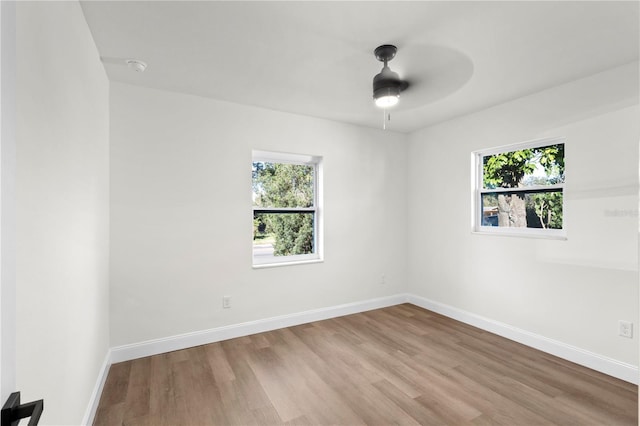 empty room with a wealth of natural light, baseboards, and wood finished floors