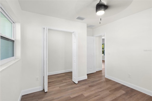 unfurnished bedroom featuring visible vents, wood finished floors, a closet, baseboards, and ceiling fan