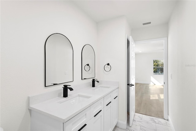 bathroom with visible vents, marble finish floor, baseboards, and a sink