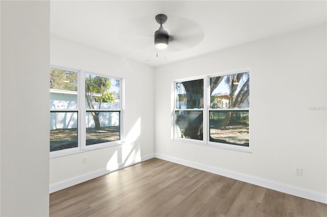 unfurnished room featuring a ceiling fan, wood finished floors, and baseboards