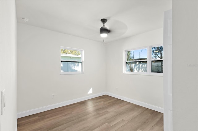 unfurnished room featuring baseboards, plenty of natural light, wood finished floors, and a ceiling fan