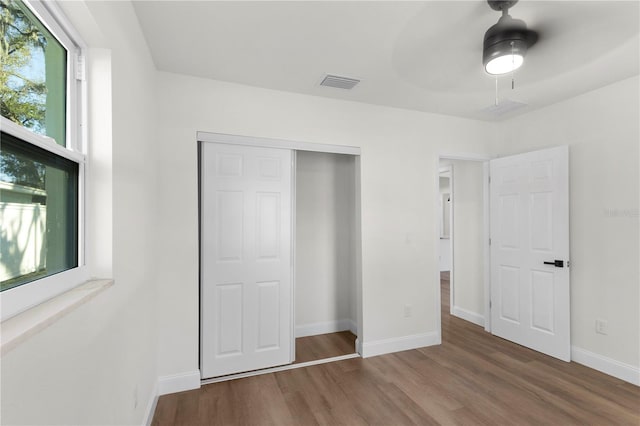 unfurnished bedroom with visible vents, wood finished floors, a closet, baseboards, and ceiling fan