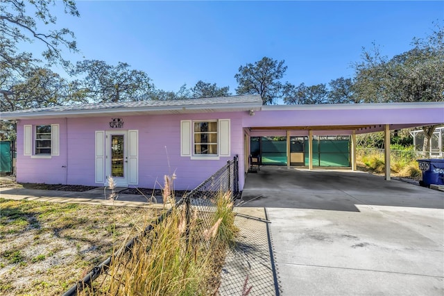 ranch-style house with driveway, fence, and a carport