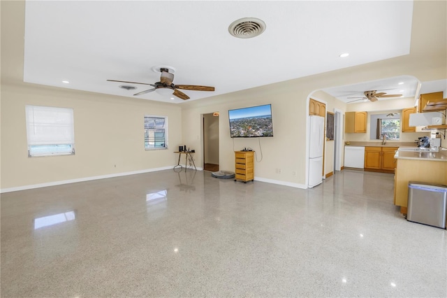 unfurnished living room with light speckled floor, arched walkways, visible vents, and baseboards