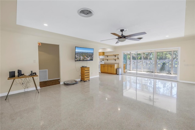 living area with speckled floor, visible vents, and baseboards