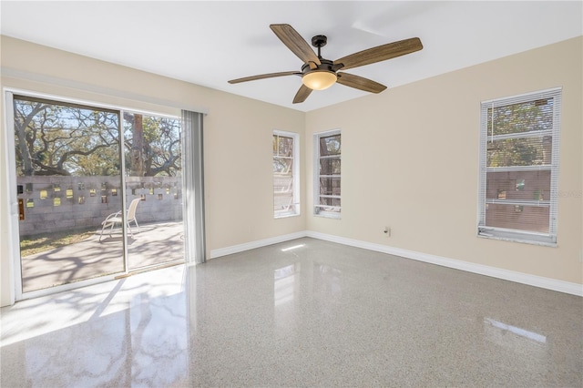 spare room featuring ceiling fan, plenty of natural light, baseboards, and speckled floor