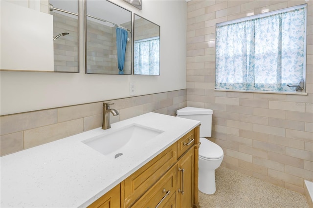 full bath with curtained shower, tile walls, toilet, and vanity