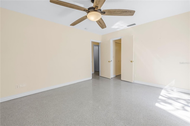 unfurnished room featuring baseboards, visible vents, a ceiling fan, and speckled floor