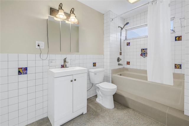 full bath with shower / tub combo, a wainscoted wall, speckled floor, vanity, and tile walls