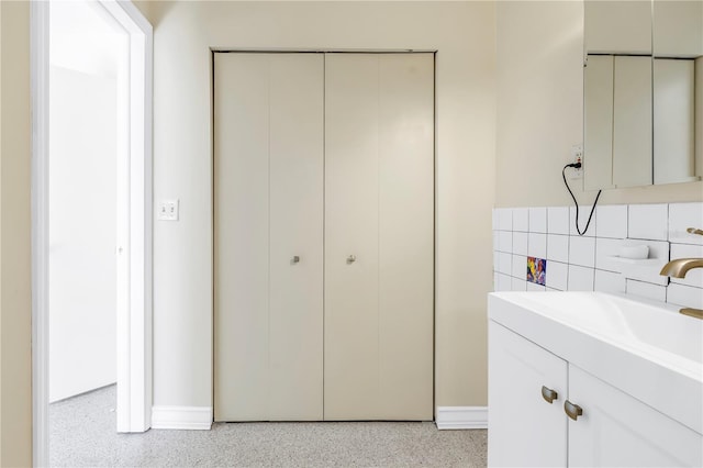 bathroom featuring vanity, decorative backsplash, and speckled floor