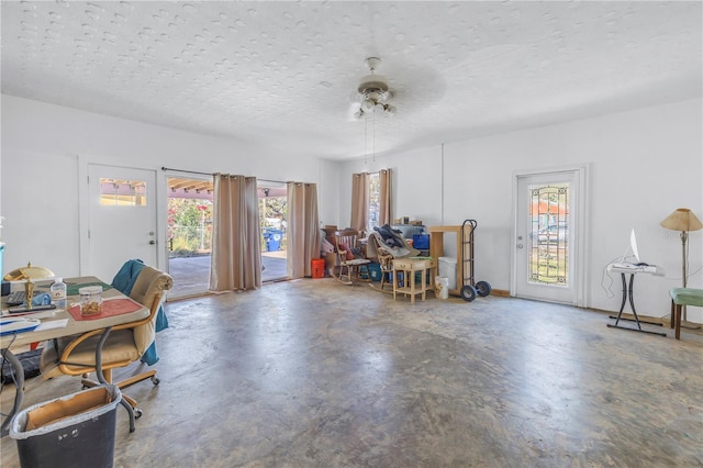 interior space with ceiling fan, a textured ceiling, and concrete flooring