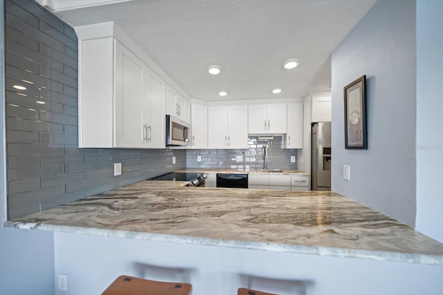 kitchen with white cabinetry, appliances with stainless steel finishes, and kitchen peninsula