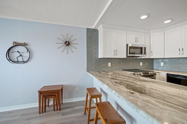 kitchen with light stone countertops, appliances with stainless steel finishes, white cabinets, and decorative backsplash