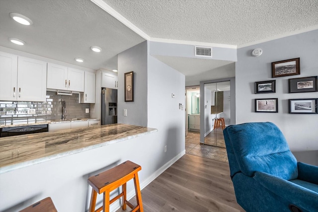 kitchen featuring white cabinetry, dishwasher, sink, decorative backsplash, and stainless steel fridge with ice dispenser