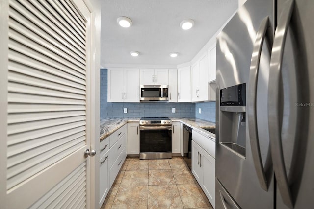 kitchen with white cabinetry, appliances with stainless steel finishes, light stone countertops, and backsplash