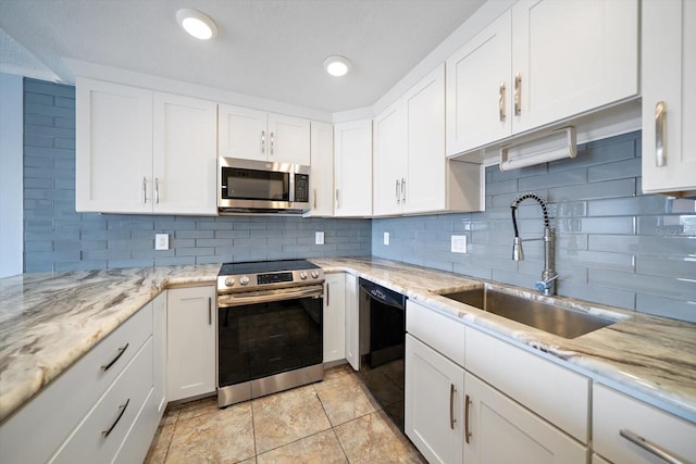 kitchen with sink, appliances with stainless steel finishes, white cabinetry, light stone counters, and decorative backsplash