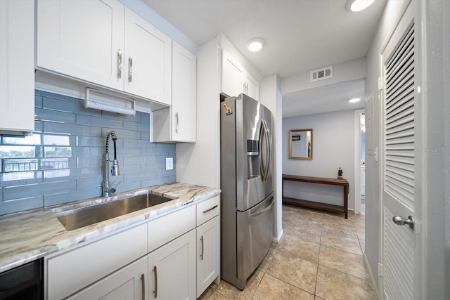 kitchen with white cabinetry, sink, stainless steel fridge with ice dispenser, and light stone counters