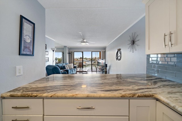 kitchen with white cabinetry, ornamental molding, and a textured ceiling