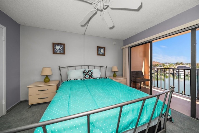 carpeted bedroom featuring ceiling fan, a water view, access to exterior, and a textured ceiling