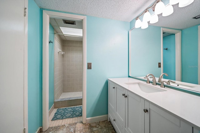 bathroom featuring a tile shower, vanity, and a textured ceiling