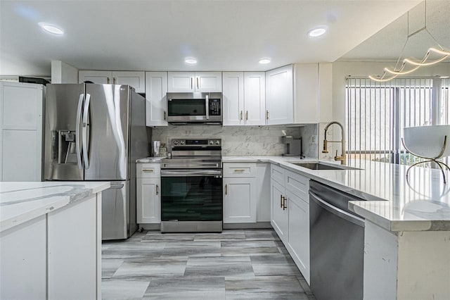 kitchen with sink, white cabinetry, hanging light fixtures, stainless steel appliances, and decorative backsplash