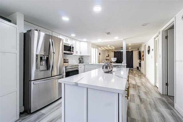 kitchen with ceiling fan, stainless steel appliances, white cabinets, decorative backsplash, and kitchen peninsula