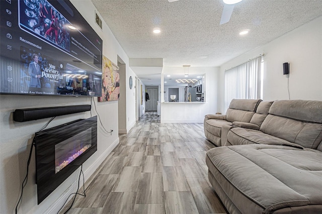 living room featuring hardwood / wood-style flooring, ceiling fan, and a textured ceiling