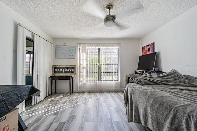 bedroom with hardwood / wood-style flooring, ceiling fan, and a textured ceiling