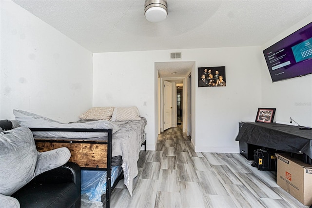 bedroom with a textured ceiling and light wood-type flooring